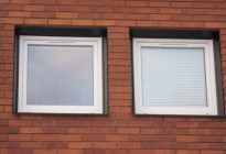 Fönsterbyte på tegelvilla. Nya PVC-fönster med svarta fönsterbleck för att matcha befintliga stilen på huset.