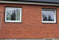 Fönsterbyte på tegelvilla. Nya PVC-fönster med svarta fönsterbleck för att matcha befintliga stilen på huset.